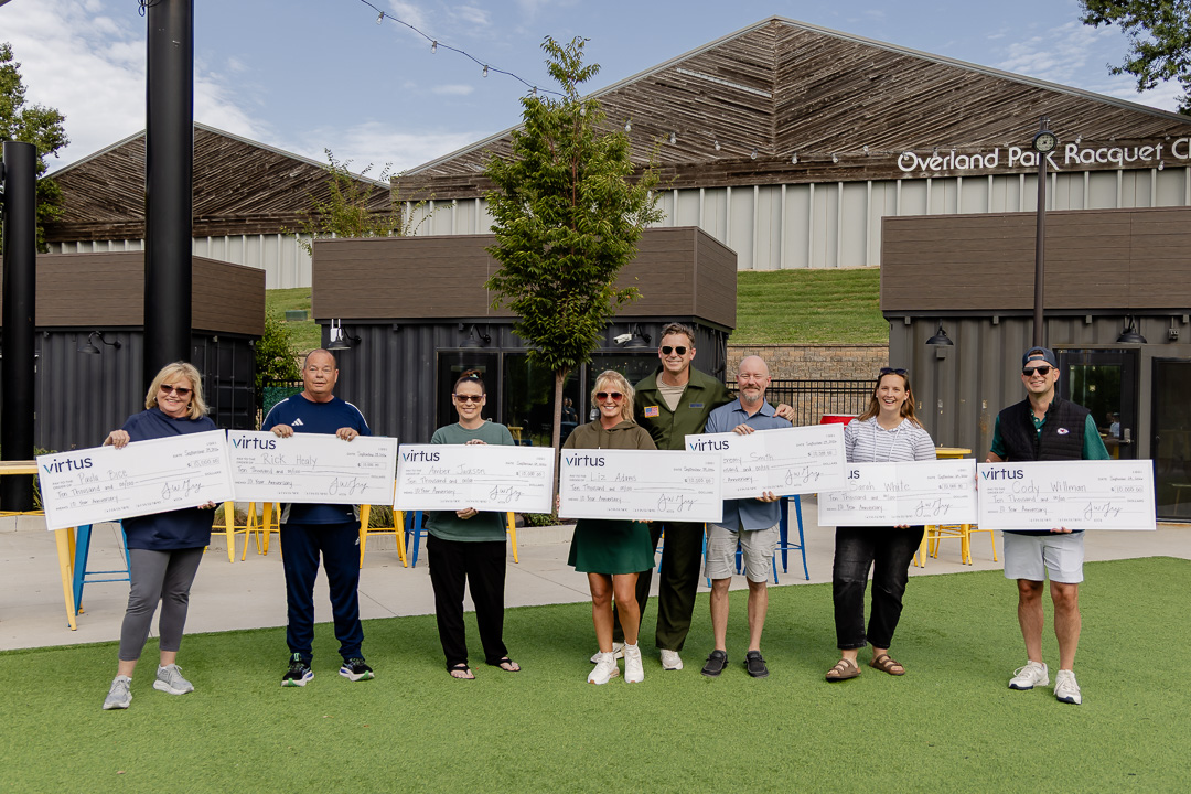 Virtus colleagues celebrating their 10-year anniversaries with presentation checks at Virtus Days.